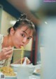 A woman eating noodles with chopsticks at a table.