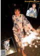 A woman in a kimono holding a sparkler in her hand.