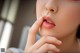 A close up of a woman's face with her hand on her chin.