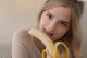 A woman holding a banana in front of her mouth.