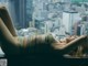 A woman laying on a window sill with her legs crossed.