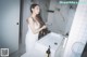 A woman in a white dress standing in a bathroom.