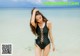 A woman in a black swimsuit standing on a beach.