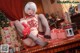 A woman in a red and white outfit sitting on a table with presents.