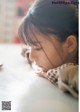 A little girl sitting at a table with her head resting on her hand.