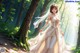 A woman in a wedding dress walking through a forest.