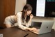 A woman leaning over a desk using a laptop computer.